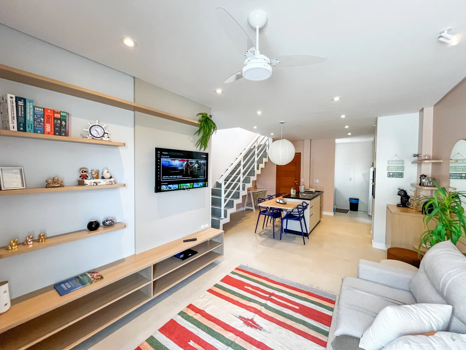 Sala de estar com sofá, TV e escada
